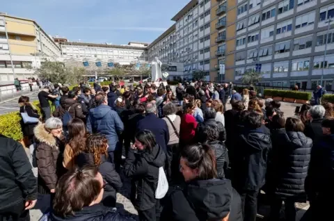 Reuters Dozens of people gather outside the Gemelli Hospital where the Pope is receiving treatment