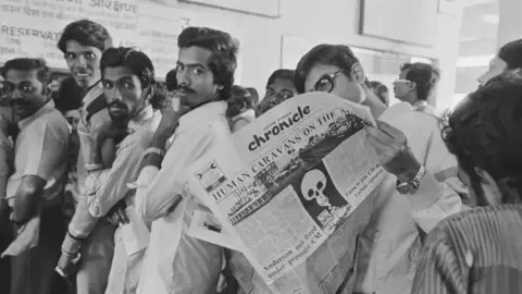 Getty Images Eleven days after a cloud from the Union Carbide plant carrying methyl isocyanate gas seriously injured 20,000 people and killed 3000, the resumption of work has been announced, provoking a new exodus. A total of 200,000 persons have fled Bhopal (which had 800,000 inhabitants). The front page of a local newspaper with a death's head. (Photo by Alain Nogues/Sygma/Sygma via Getty Images)<br />