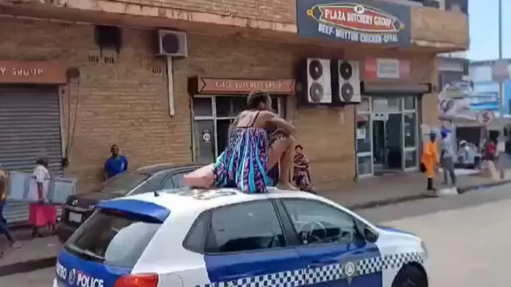 Woman taken to hospital after she climbed on top of police vehicle and stripped naked (video)