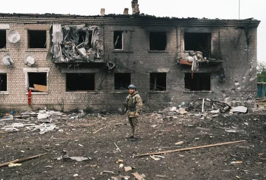 A Ukrainian police officer inspects a damaged building during the evacuation of local people from territories bordering Russia, in the city of Vovchansk, Kharkiv region, northeastern Ukraine