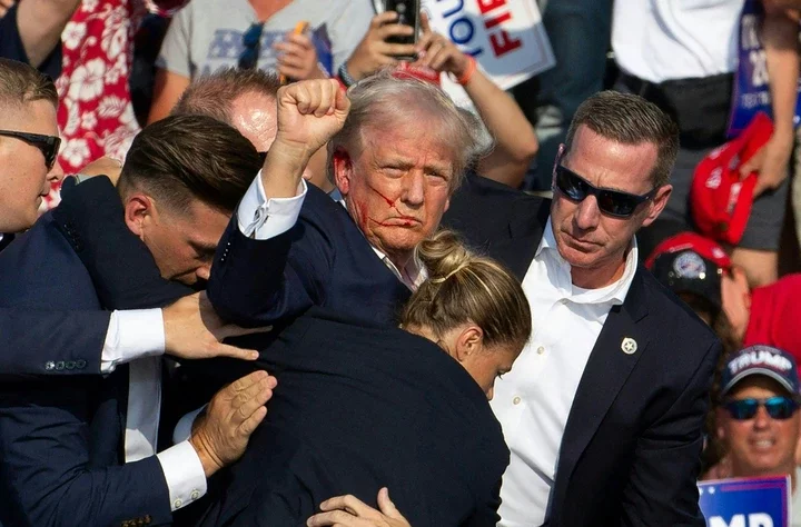 Donald Trump, bleeding from the face, is helped off stage by Secret Service agents at a campaign event.