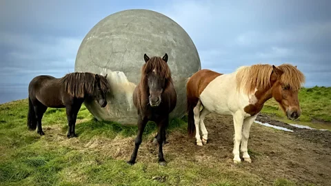 Michelle Gross Tourists - and Icelandic horses - seek out the island's Orbis et Globus concrete ball (Credit: Michelle Gross)