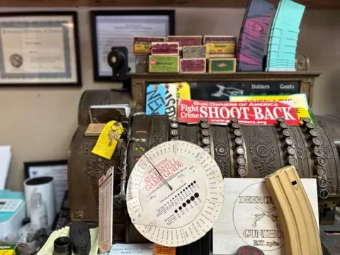 A vintage cash register is adorned with a sign that says 'fight crime, shoot back