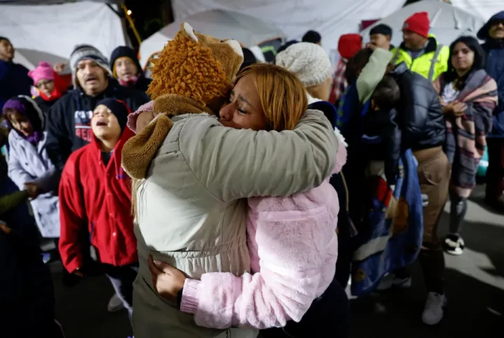 Two asylum seekers embrace and cry at a temporary shelter.