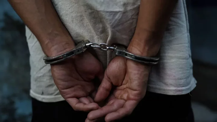 A man sits handcuffed after being arrested in San Salvador. [Getty Images]