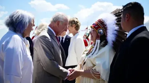 Reuters Britain's King Charles meets with an elder as he and Queen Camilla arrive at Ottawa Airport in Ontario, Canada, as the queen wears a pale pink fringed coat dress and a Maple leaf diamond brooch gifted to HMQ Elizabeth the Queen Mother by George VI, worn by QE2 for her first ever visit to Canada in 1939, May 26, 2025.