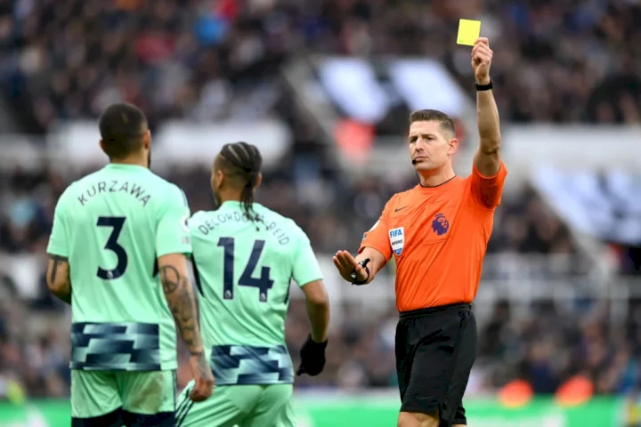 Premier League referee Robert Jones shows a yellow card to Fulham player Layvin Kurzawa