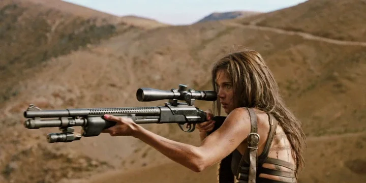 A woman in the desert aiming a gun in Revenge