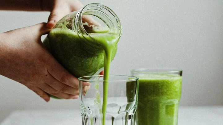 Someone pouring green juice into a glass