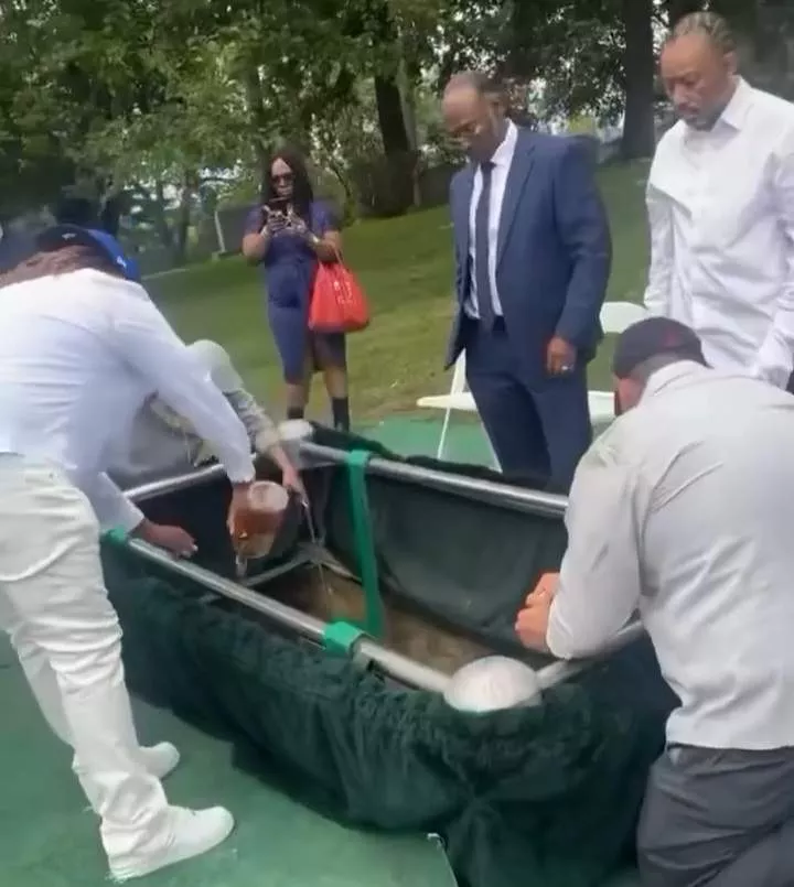 Loved ones pour bottles of liquor into grave at funeral (videos)