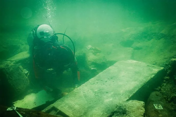 A diver looks at a stone block underwater