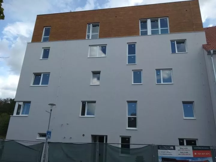 Four-story modern apartment building with several mismatched windows of different heights, widths, and number of panels