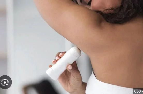 A lady applying deodorant on her body