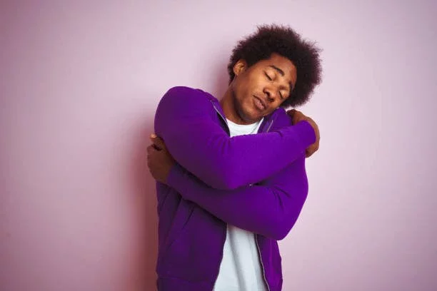 Young African American Man Wearing Purple Sweatshirt Standing Over Isolated Pink Background Hugging Oneself Happy And Positive Smiling Confident Self Love And Self Care Stock Photo - Download Image Now - iStock